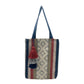 woven tote bag with vertical stripes in blue, beige, and red, featuring a decorative tassel. The bag is hanging