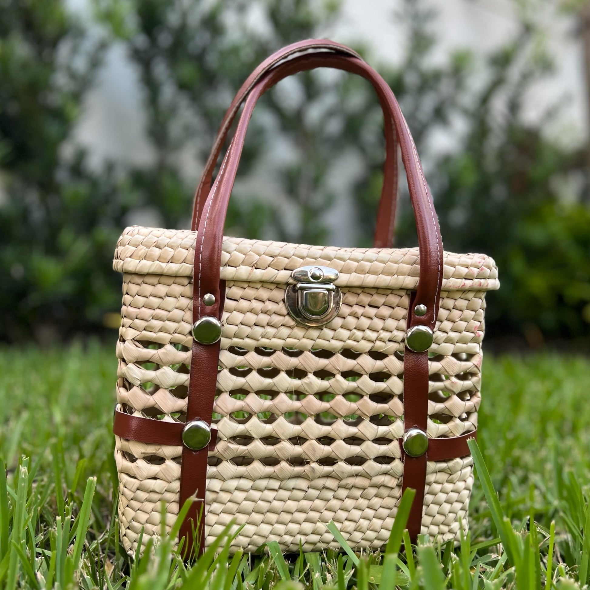 woven palm handbag with brown leather straps and silver clasp