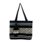 black tote bag with a horizontal band of geometric woven patterns in cream and a matching tassel