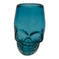 Mexican shot glass, shaped like a skull and crafted from eco-friendly recycled glass. The glass has a vibrant teal color and holds approximately 2 fluid ounces.