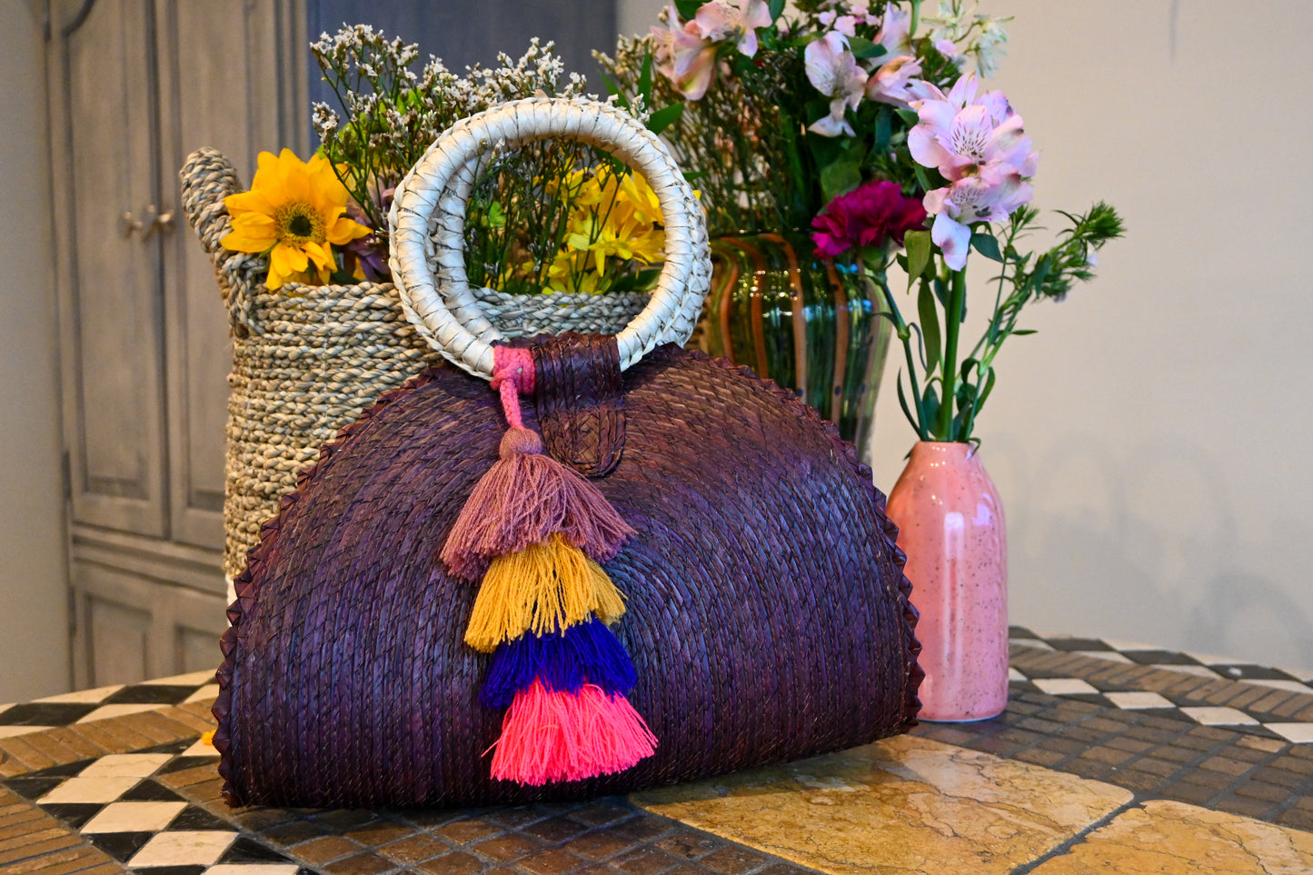 purple woven palm handbag with a circular handle wrapped in light material.