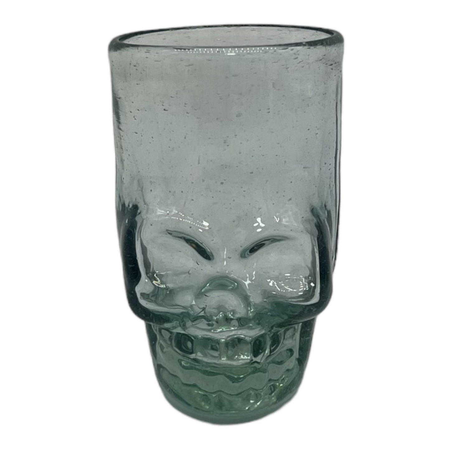 Mexican shot glass, shaped like a skull and crafted from eco-friendly recycled glass. The glass is translucent with a subtle greenish tint and holds approximately 2 fluid ounces.