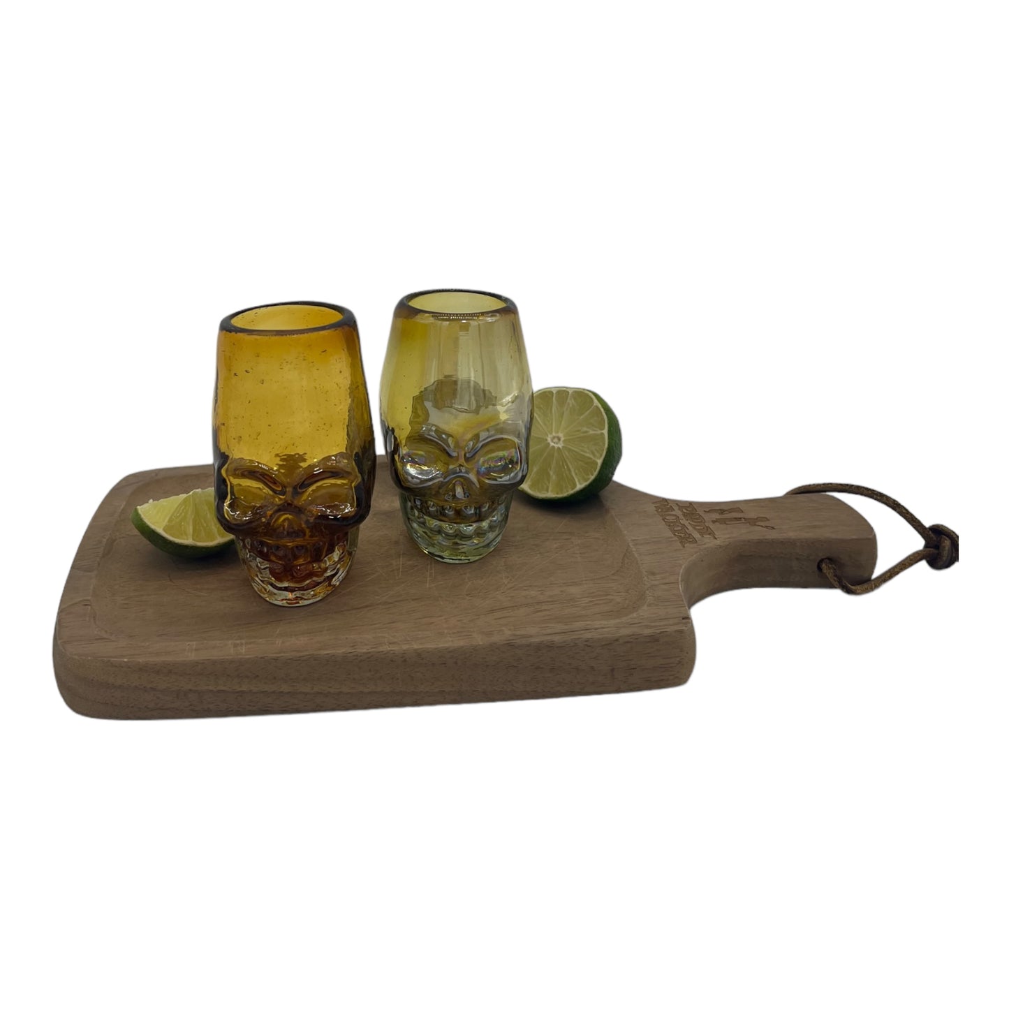 handblown Mexican shot glass, shaped like a skull and crafted from eco-friendly recycled glass. It features a gradient color scheme transitioning from dark at the base to a lighter amber at the top. The glass holds approximately 2 fluid ounces.