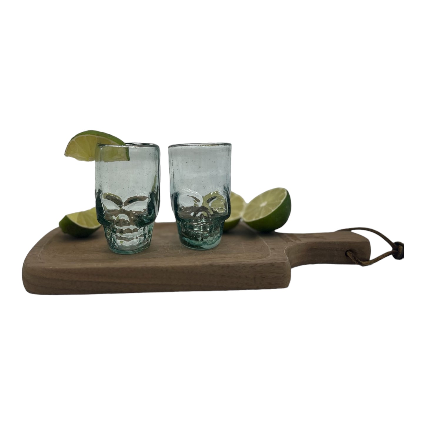 Mexican shot glass, shaped like a skull and crafted from eco-friendly recycled glass. The glass is translucent with a subtle greenish tint and holds approximately 2 fluid ounces.