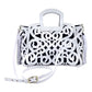 white leather tote with an intricate scroll pattern, handle, adjustable shoulder strap, and side tassels.