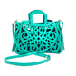 turquoise leather tote with an intricate scroll pattern, handle, adjustable shoulder strap, and side tassels.