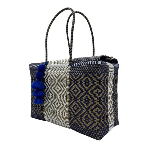 geometric patterns in navy blue, white, and tan. It has matching handles and is adorned with navy blue tassels.