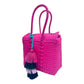 bright pink, woven handbag with two handles, adorned with a colorful tassel decoration.