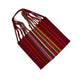 handwoven tote featuring red with blue, green, and pink stripes, and a central section with multicolored stripes. The straps are braided with various colors.