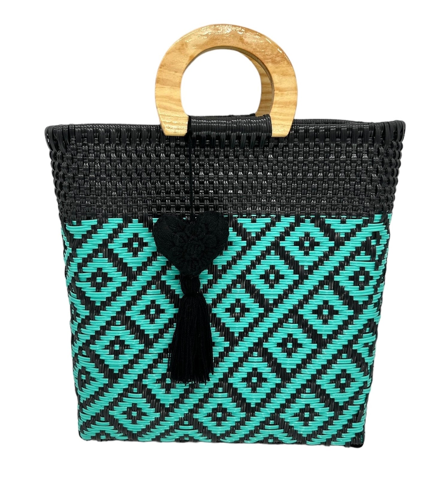 black woven tote bag made of recycled plastic with a wooden circular handle. The bag features a geometric pattern in turquoise and is adorned with a heart-shaped charm with a tassel.