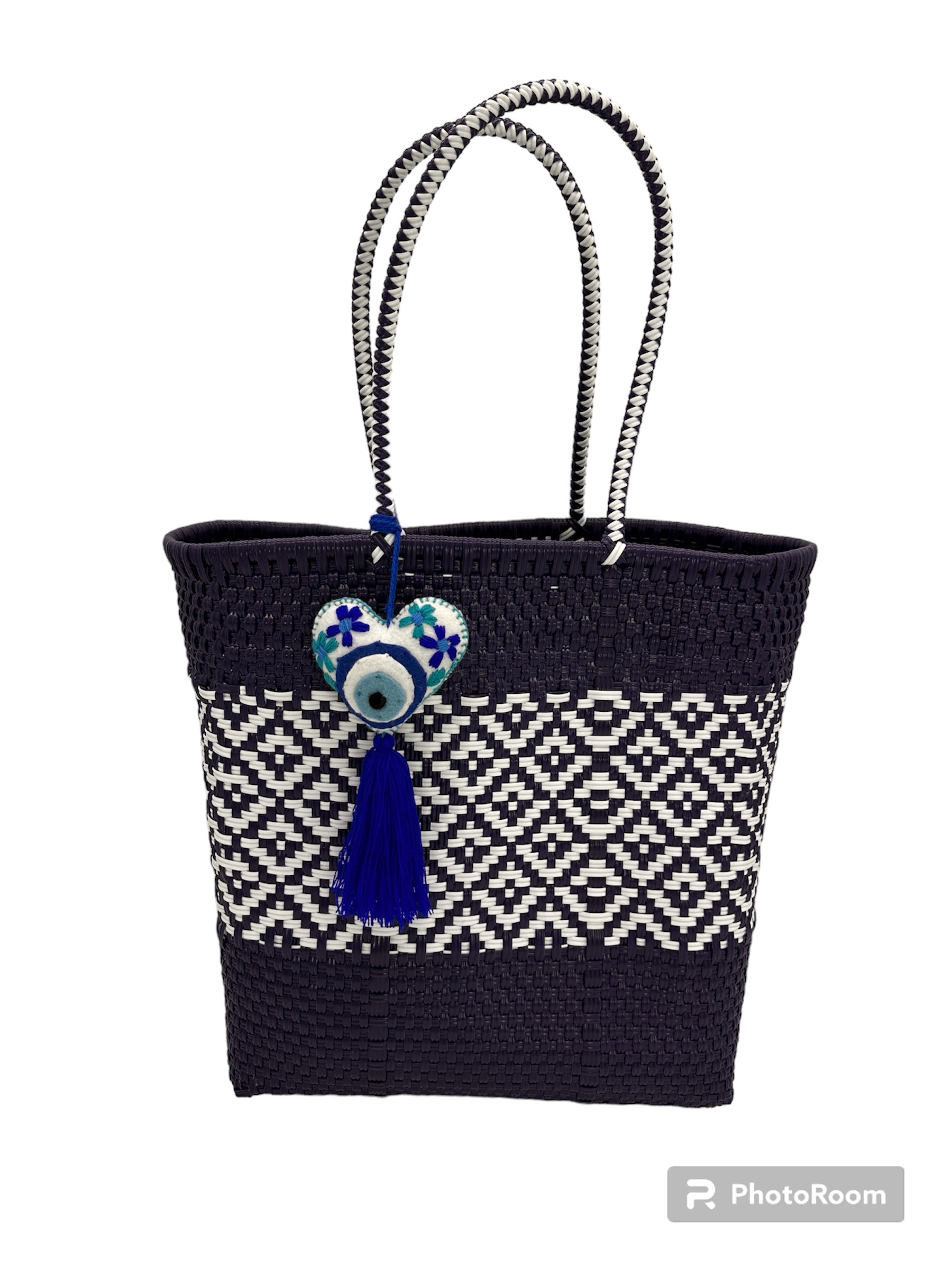 woven dark blue handbag with white geometric patterns, featuring two handles and a heart charm with tassel.