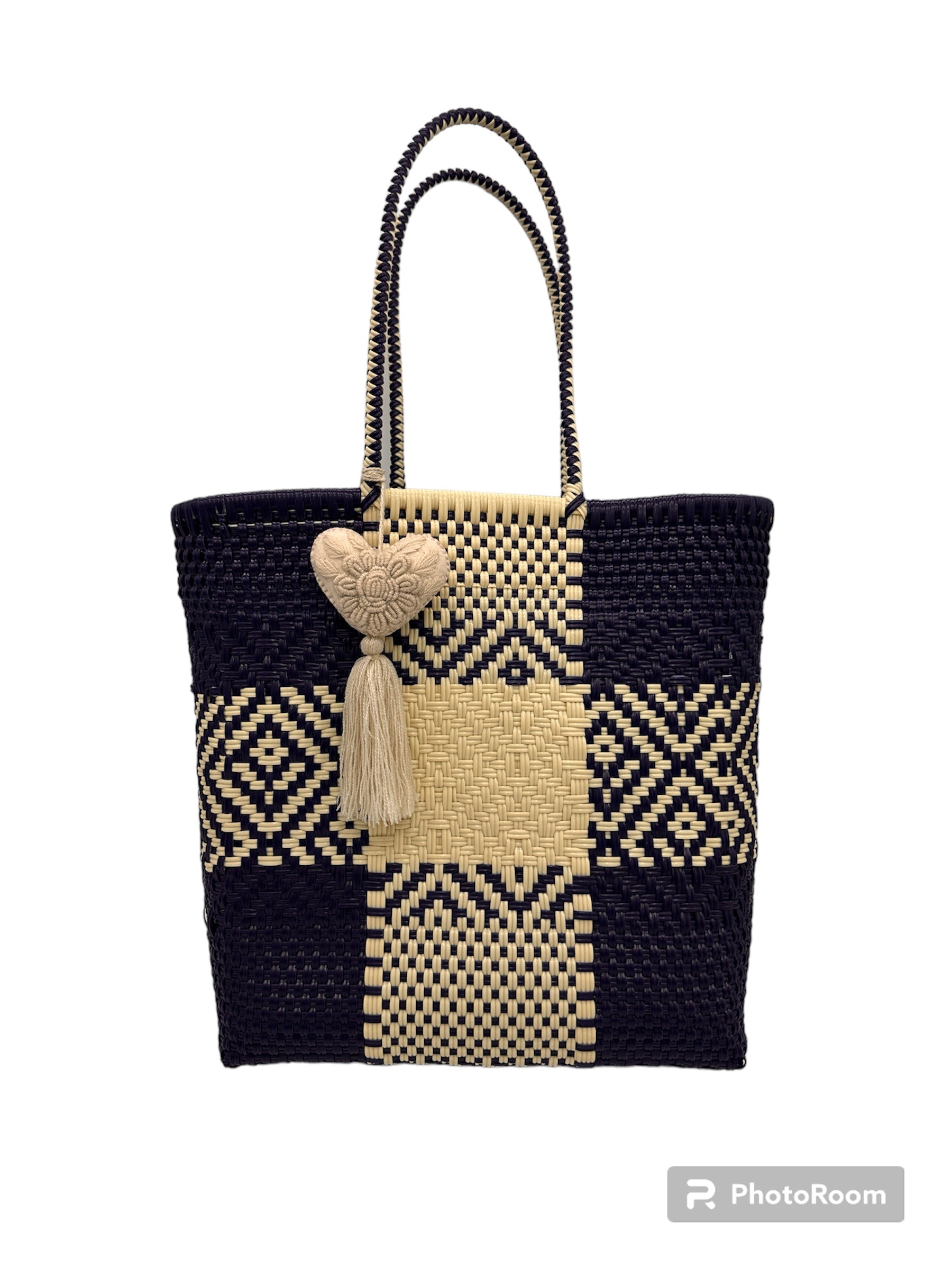 woven handbag with black and beige checkered patterns, featuring two handles and a heart-shaped charm with a tassel.