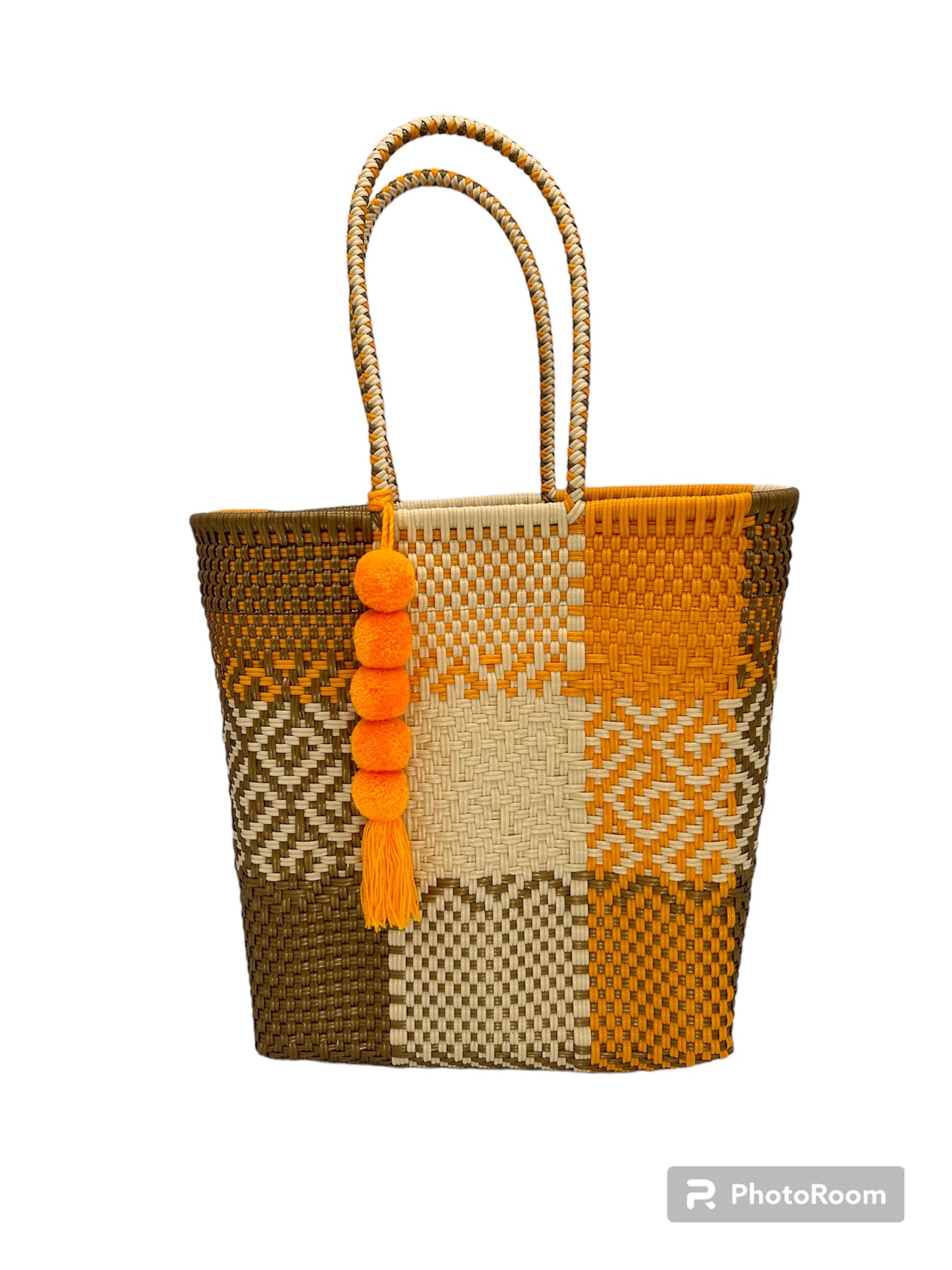 woven handbag with brown, beige, and orange checkered patterns, featuring two handles and an pom-pom charm with a tassel.