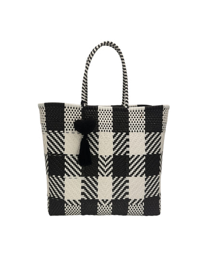 black and white checkered tote bag with two handles and a small black heart and tassel attached.