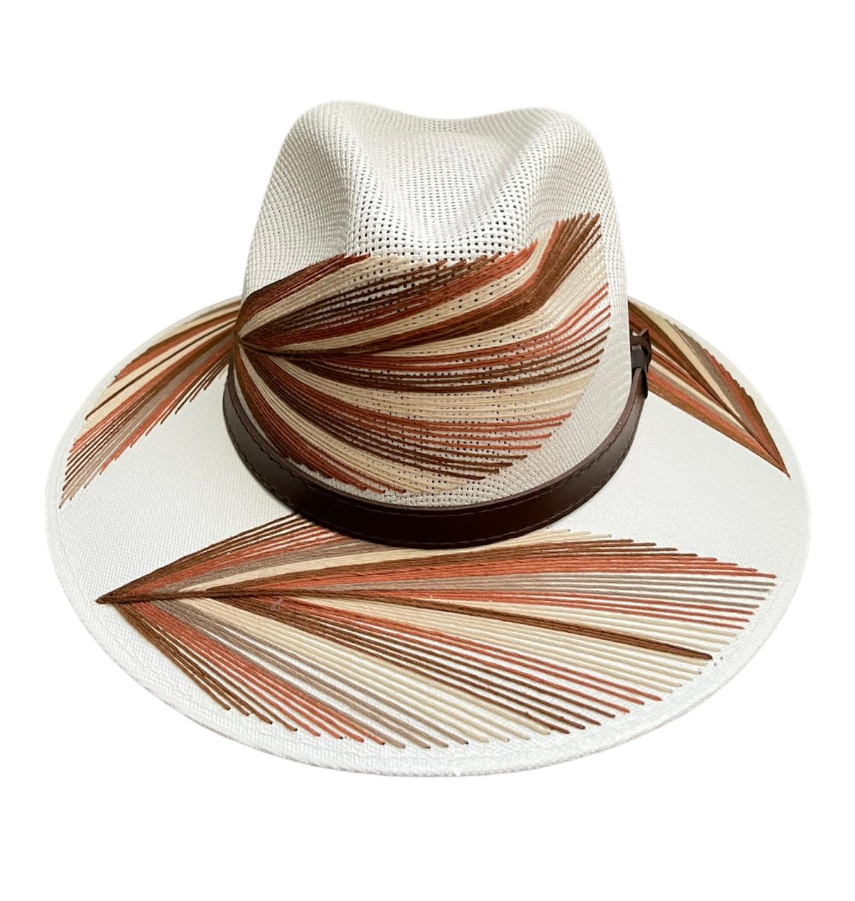 white hat with a wide brim featuring brown and beige painted designs resembling palm fronds. It has a brown leather band around the base of the crown.