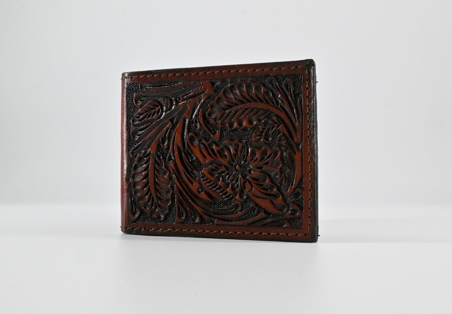 handmade, hand-carved leather bi-fold wallet in a rich brown color with intricate floral detailing.