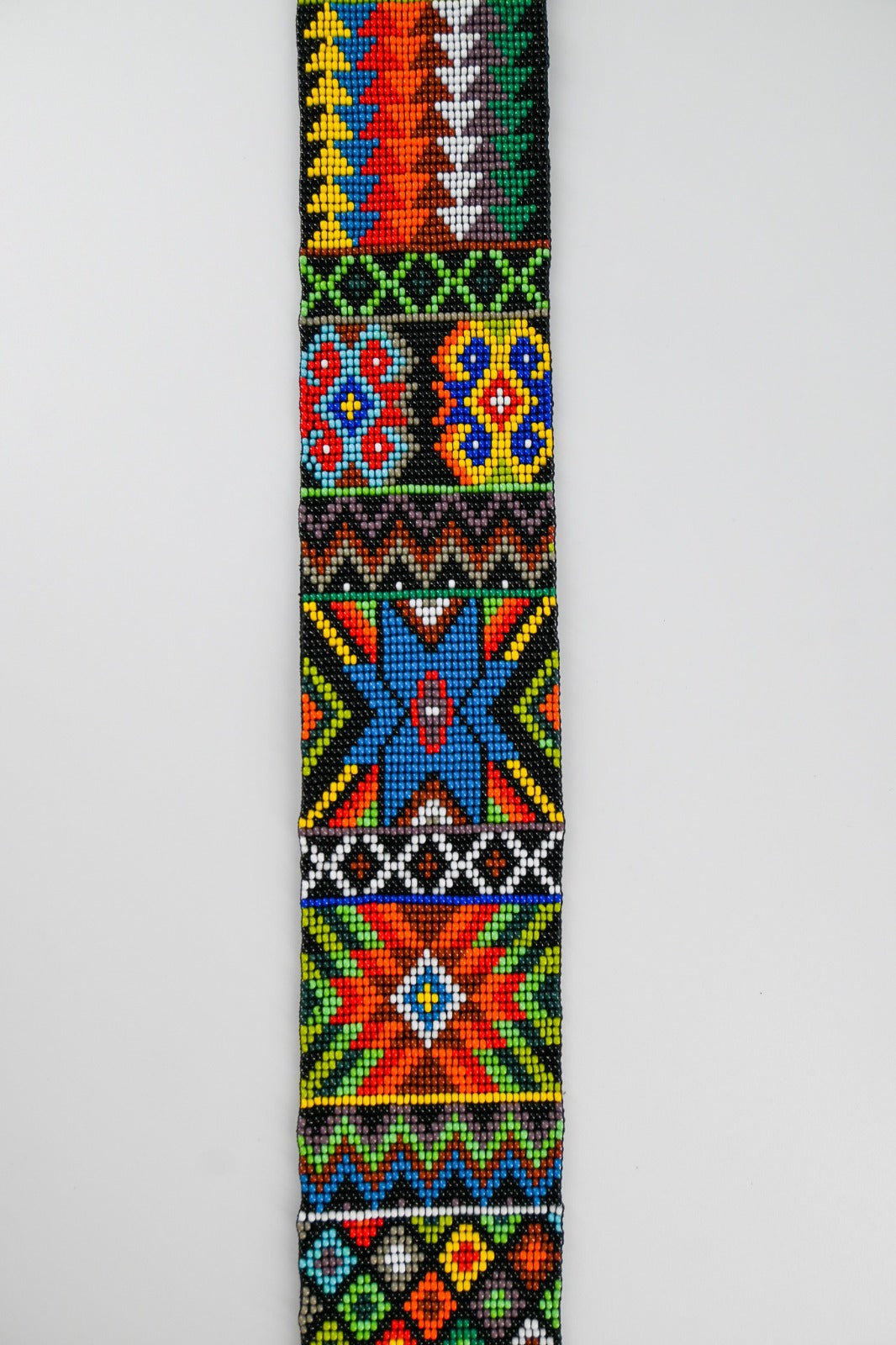 Close-up of a colorful beaded strap with intricate geometric and floral patterns in vibrant hues, showcasing detailed craftsmanship.