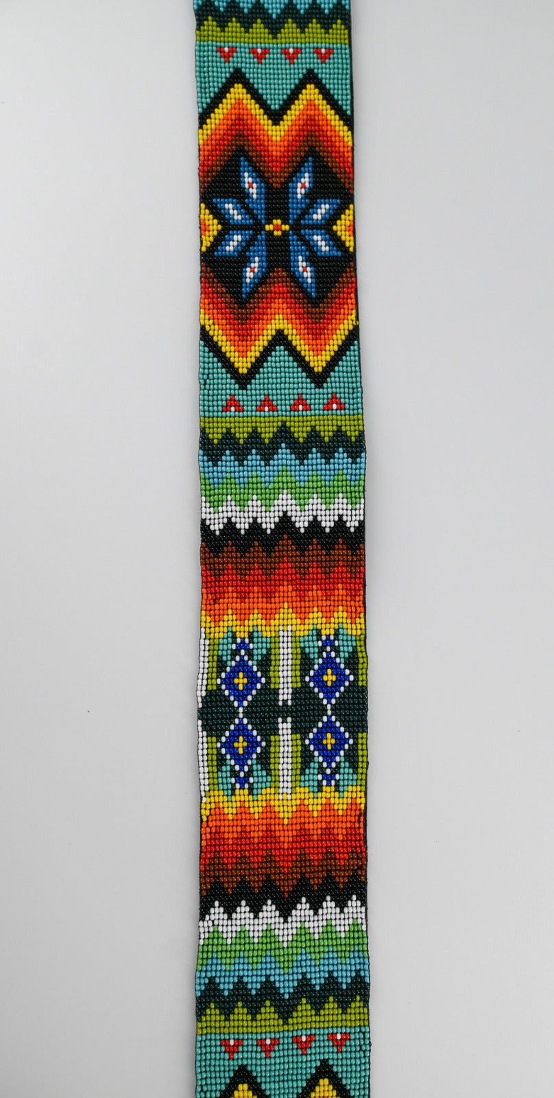 Close-up view of a colorful beaded strap with intricate traditional patterns, showcasing vibrant geometric designs and detailed craftsmanship.