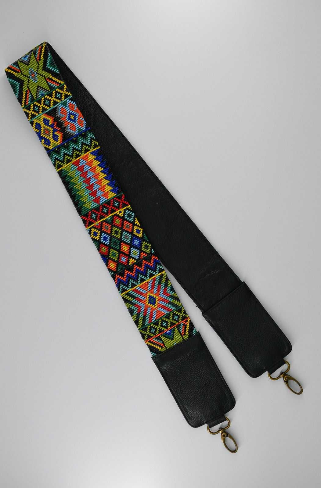 Colorful beaded strap with intricate geometric patterns and black leather ends, featuring metal clasps for attachment.