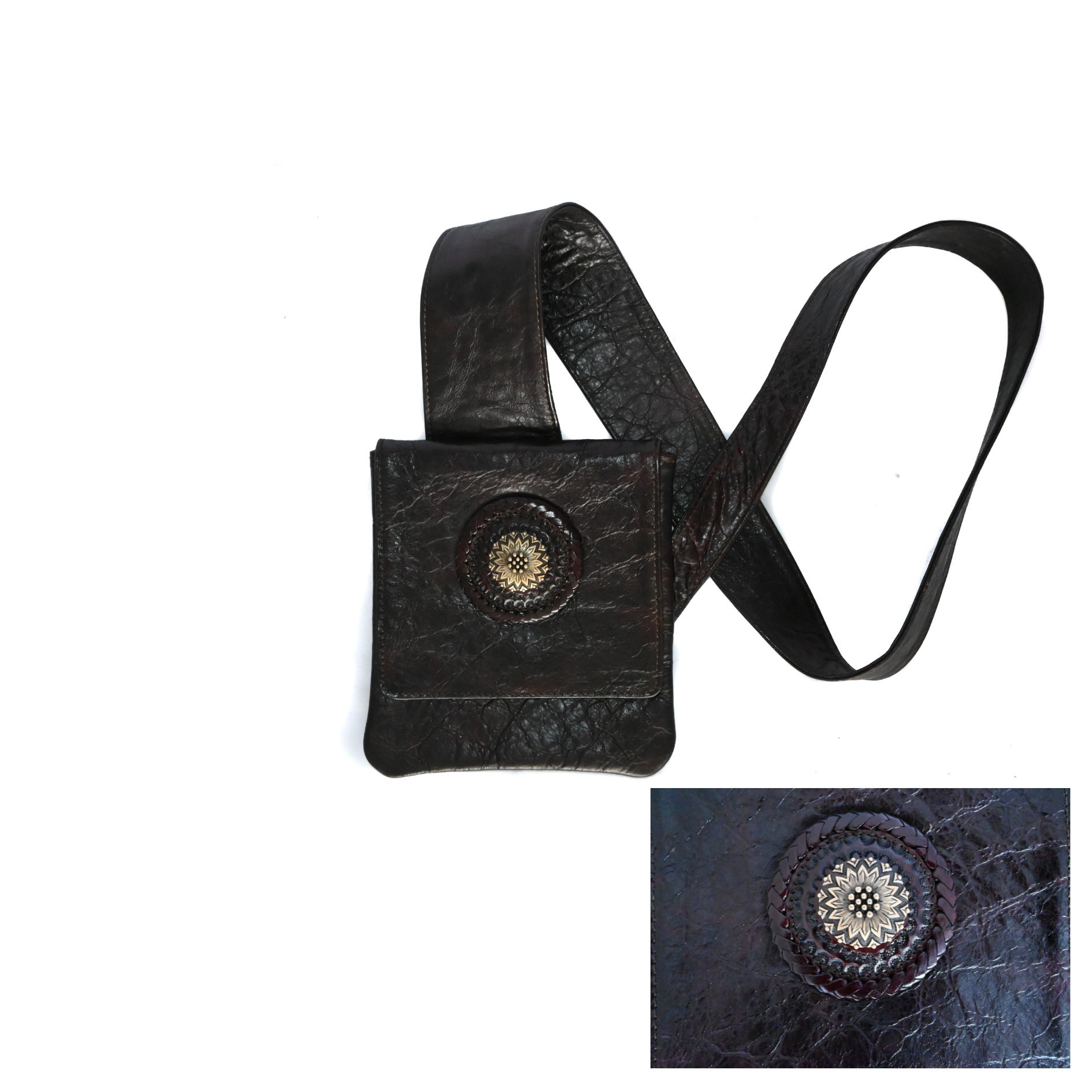 black leather crossbody bag with an ergonomic strap. It features a circular medallion design with intricate detailing on the front flap, which has a snap closure. The bag is lined with suede.