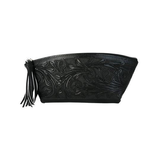 black leather cosmetic bag with hand-tooled floral patterns on both sides. It features braided seams, a full zipper top, a sueded interior, a decorative tassel, and brass studs at the bottom.