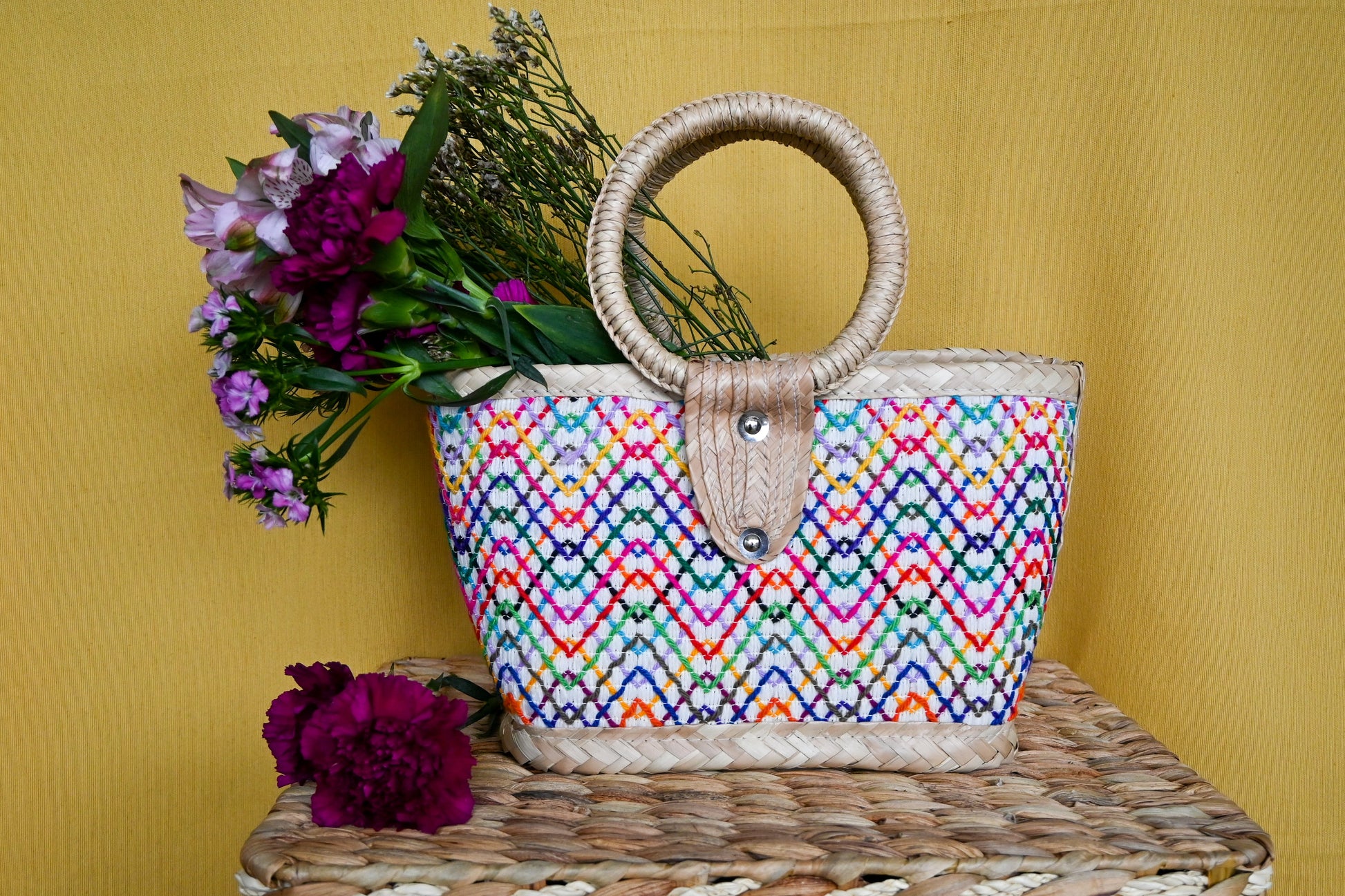 woven handbag with a colorful, patterned body and a circular handle