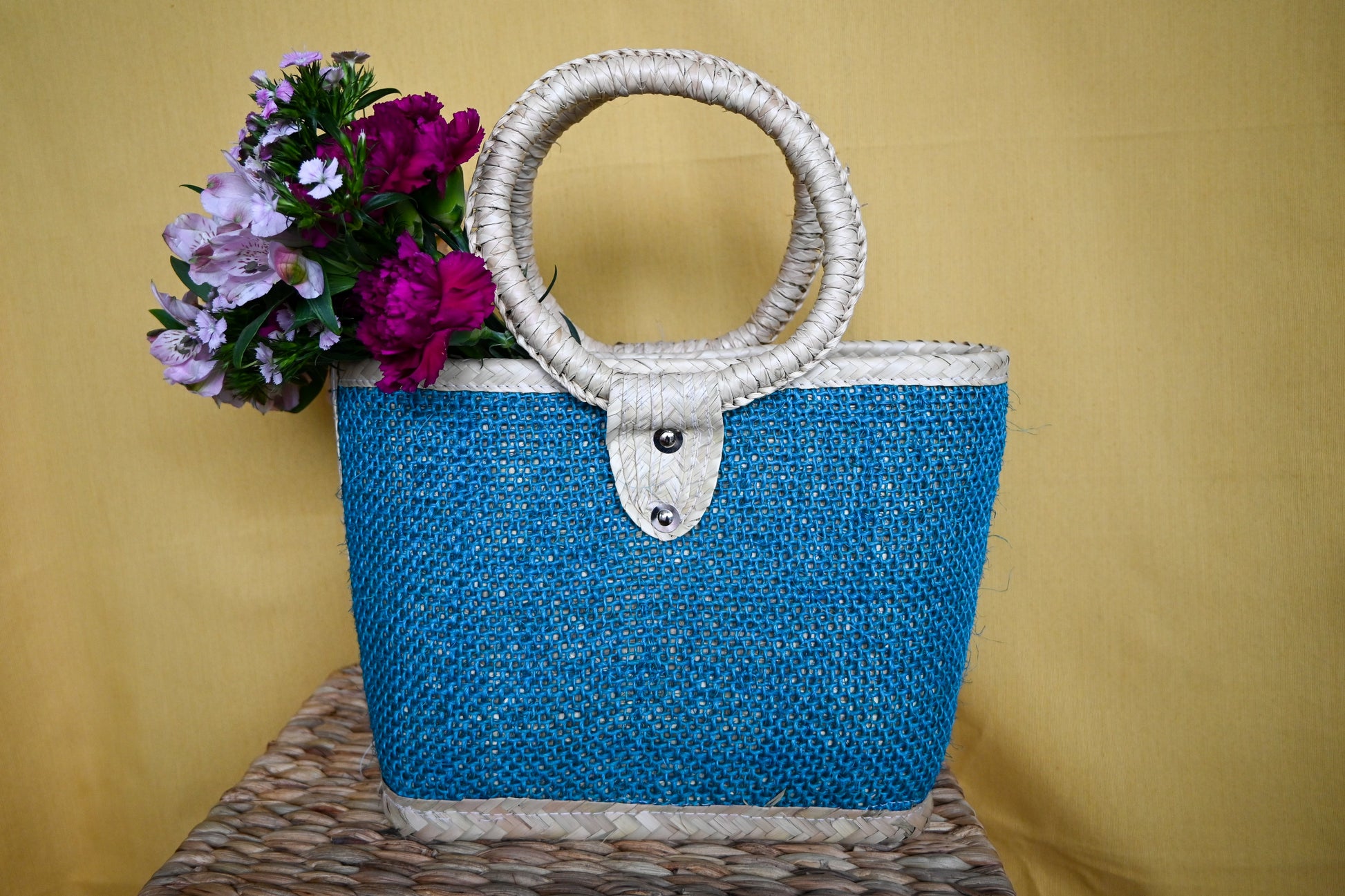 woven handbag with a turquoise body and a circular handle