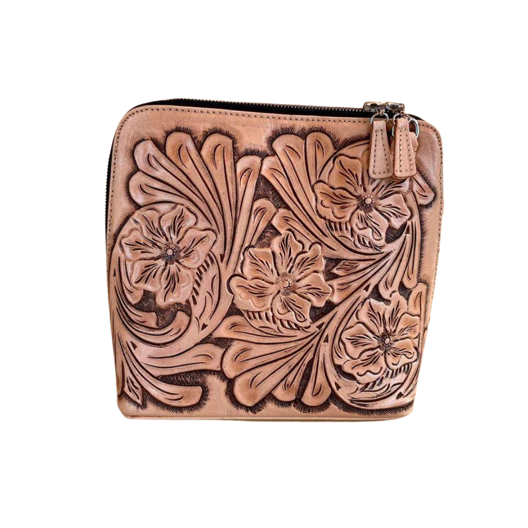 tan shoulder bag with intricate hand-carved floral details on the front panel, featuring a zip-around closure.