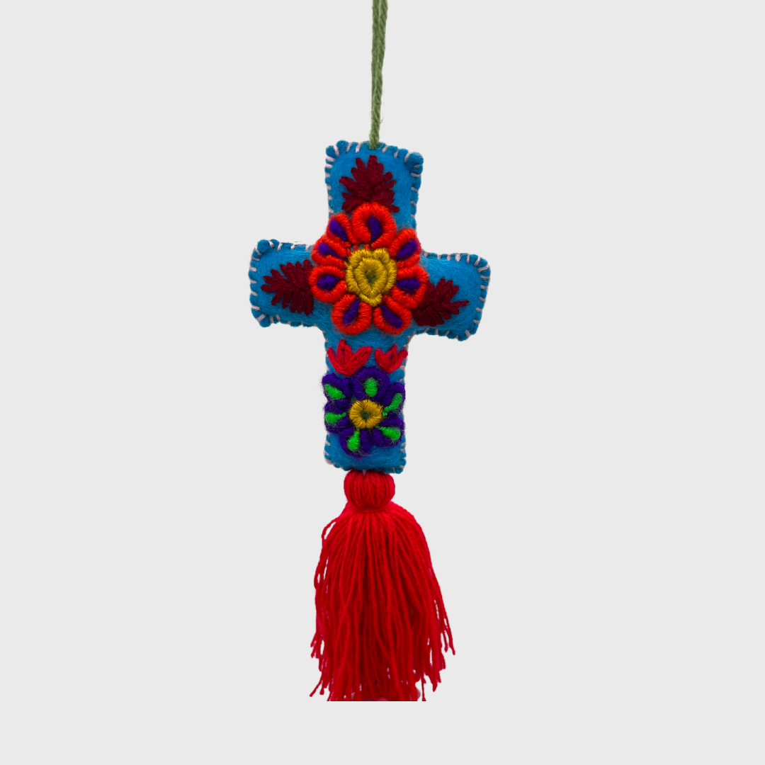 decorative hanging ornament featuring a blue cross adorned with colorful embroidered flowers and a red tassel at the bottom.