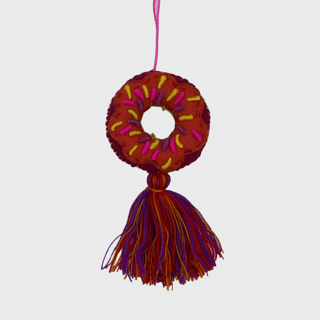 decorative hanging ornament shaped like a donut, featuring colorful sprinkles and a multicolored tassel at the bottom.