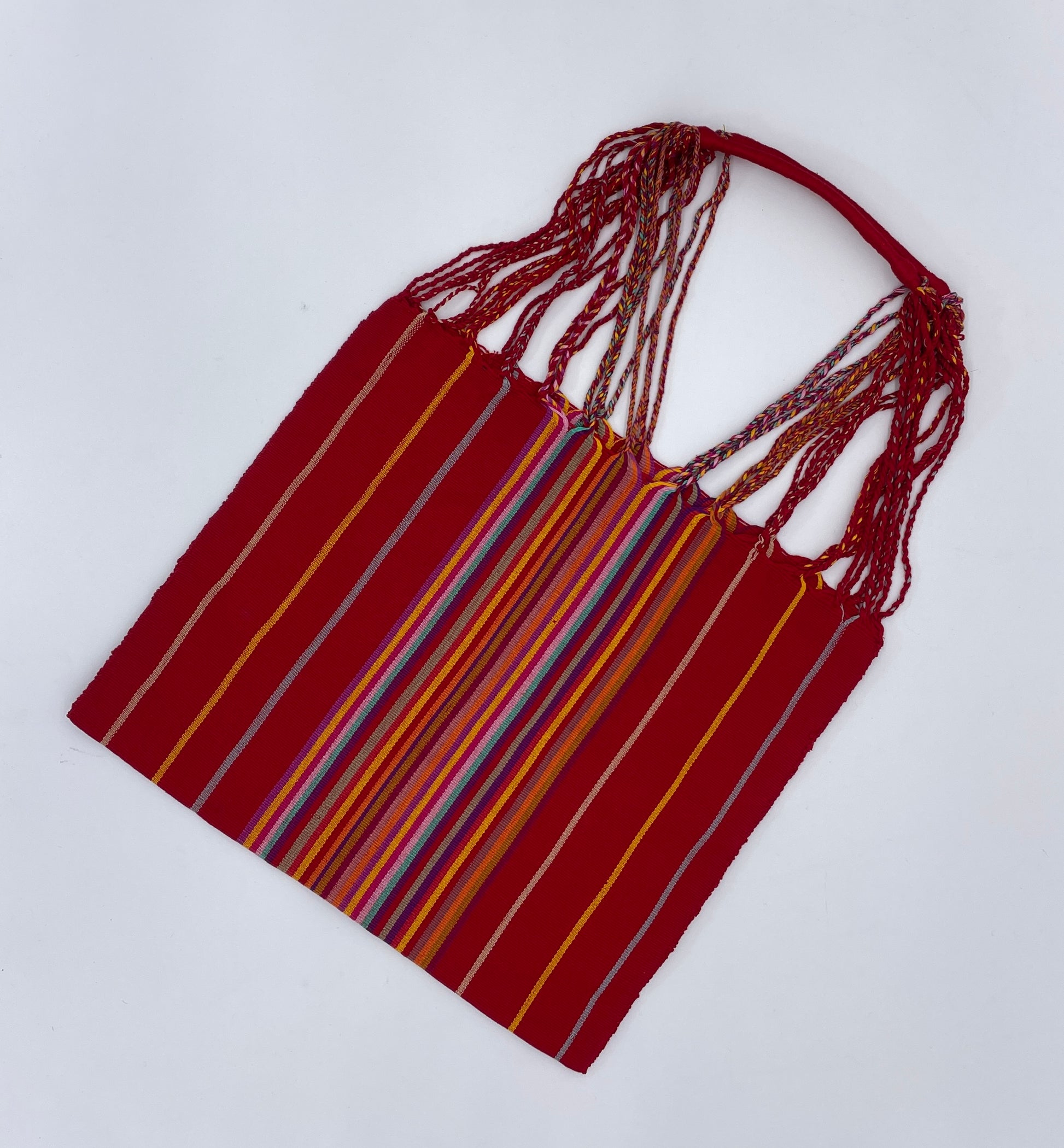 handwoven tote bag featuring vibrant, multicolored stripes on a red background with intertwined straps