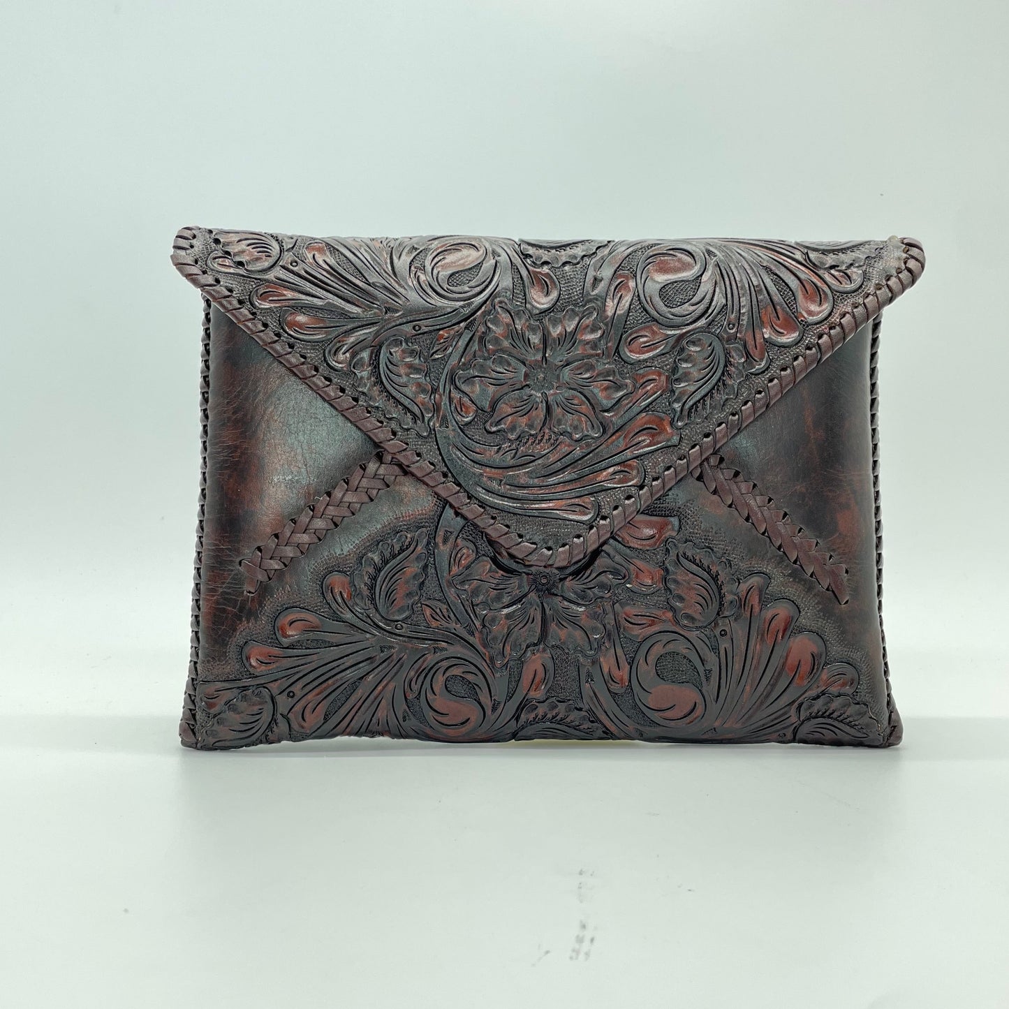 dark brown crossbody bag with a detailed embossed floral pattern on the front flap.