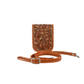 honey-colored crossbody sling bag with intricate leaf carvings on the front panel. It features a hand-braided leather strap.