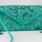 turquoise leather clutch with intricate floral carvings, long side tassels, and a matching strap. It has a snap front closure.