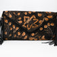 black leather clutch with hand-carved floral designs and brown accents. It features long side tassels and a snap front closure.