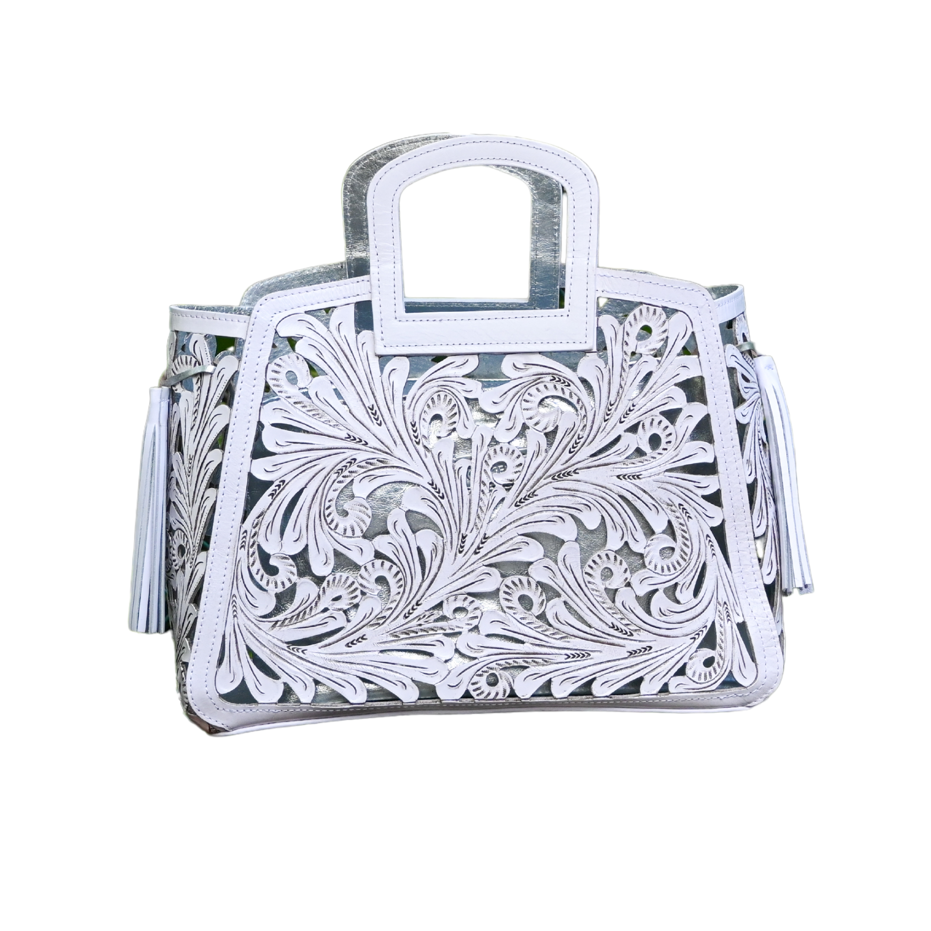 handbag with intricate, swirling cut-out designs in white leather overlaying a metallic silver background. The bag features a rectangular handle and leather tassels on the sides.