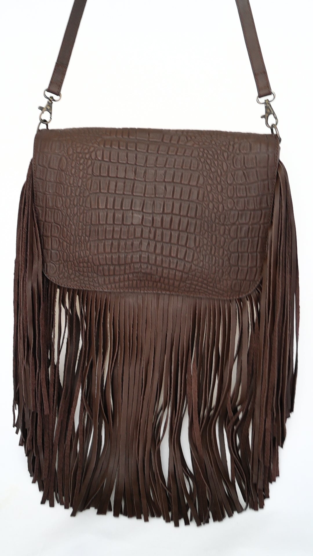 brown leather crossbody bag with a crocodile pattern on the flap and long fringe hanging from the bottom. The bag has an adjustable shoulder strap