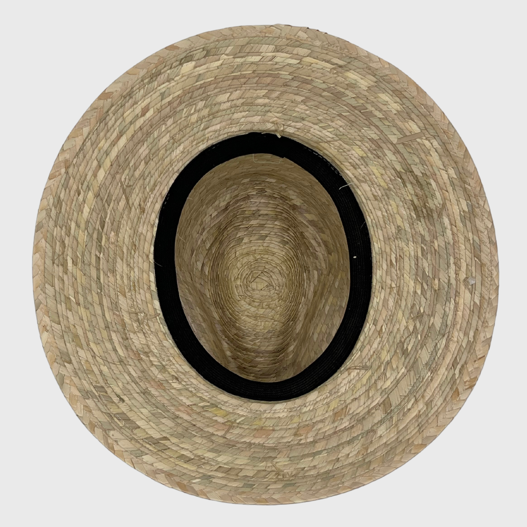 Top-down view of the inside of a handwoven hat, displaying its natural fiber construction and black inner band