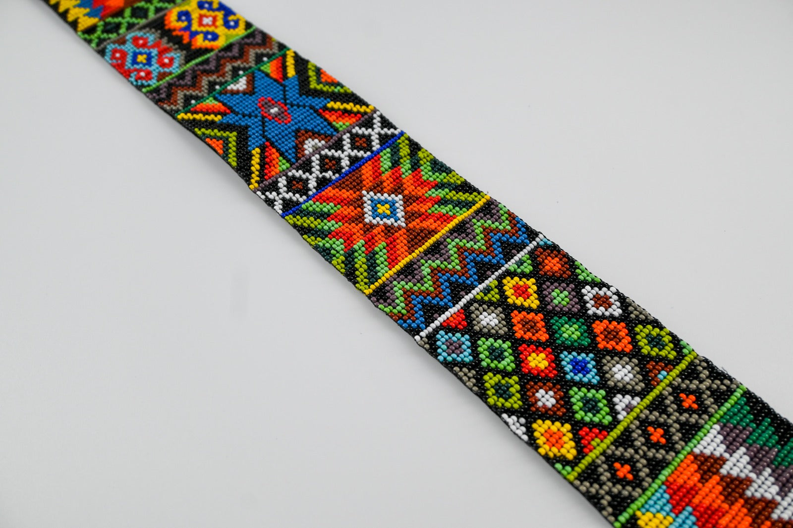 Close-up of a colorful beaded strap with intricate geometric and floral patterns in vibrant hues, showcasing detailed craftsmanship.