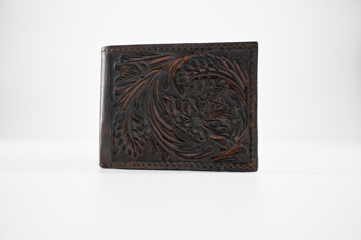 handmade, hand-carved leather bi-fold wallet in burgundy with intricate detailing.