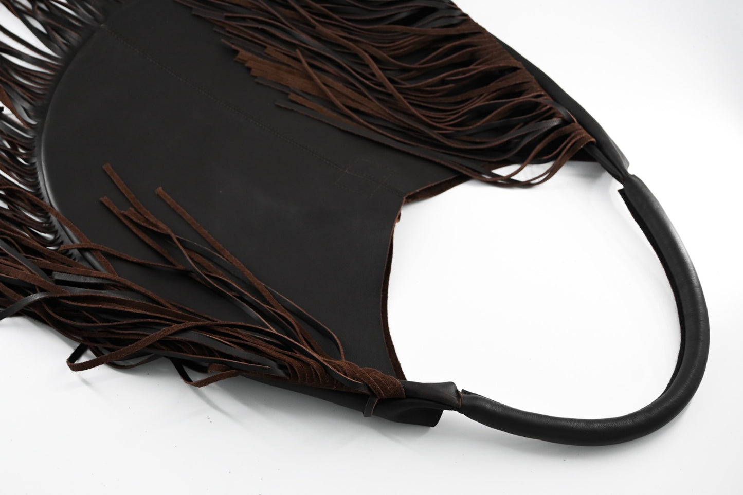 dark brown leather bag with long fringe details along the sides and bottom, featuring a padded wrapped shoulder strap.