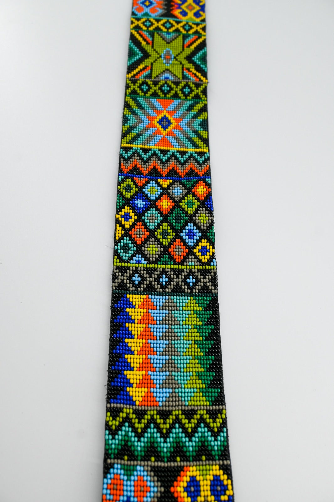 Close-up view of a colorful beaded strap with intricate traditional patterns, showcasing vibrant geometric designs and detailed craftsmanship.