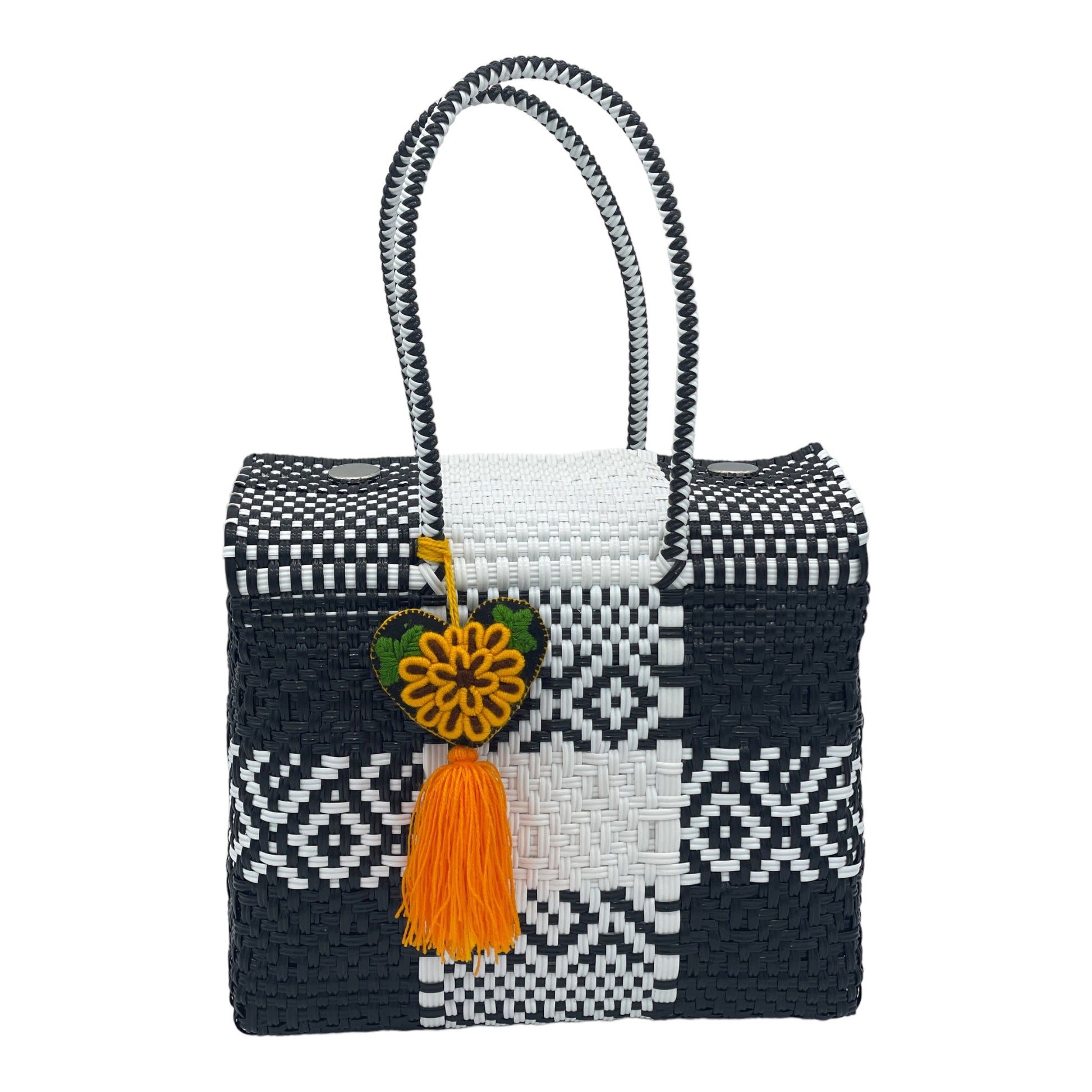 black and white woven handbag with geometric patterns, featuring a decorative pompon with a heart