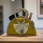 yellow crescent handbag made of palm leaves, featuring a braided white tassel and a woven handle,