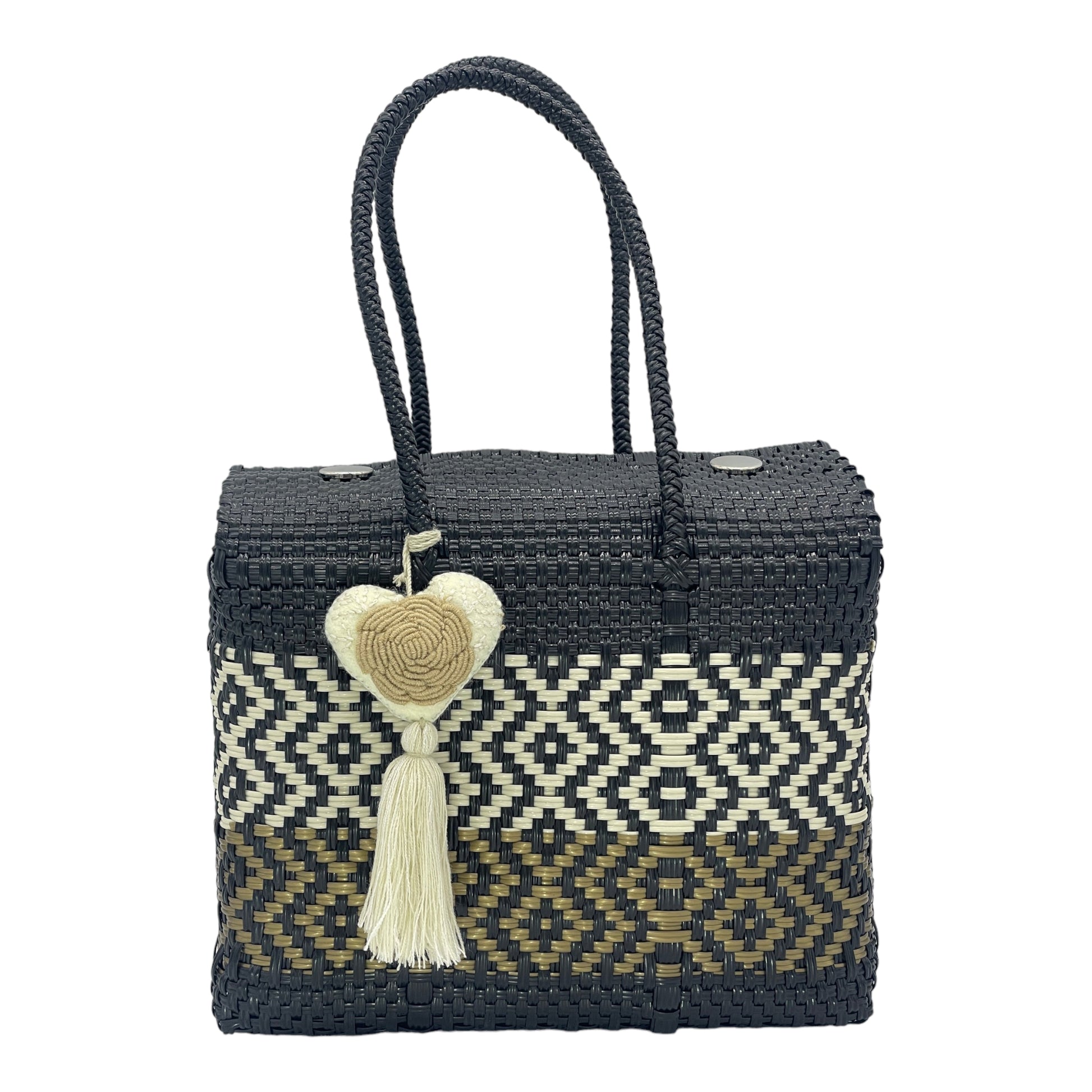 black, white, and brown woven handbag with geometric patterns, featuring a decorative  tassel with a heart.