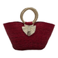 large red woven tote bag made of palm fibers with a circular handle. The bag features a decorative tassel.