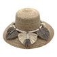 woven straw hat with a wide brim, decorated with beige and taupe tassels and a braided band around the crown. The hat has a natural straw color.