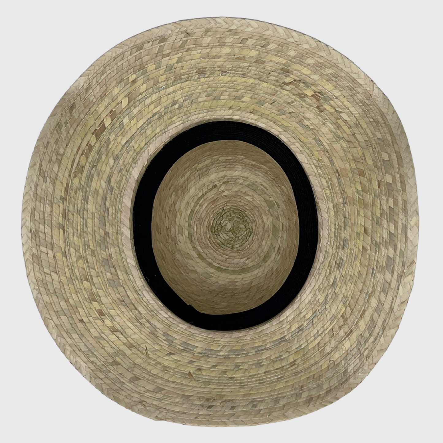 top-down view of the inside of a woven straw hat, showing the concentric circular pattern of the weave and the black inner band for fit.